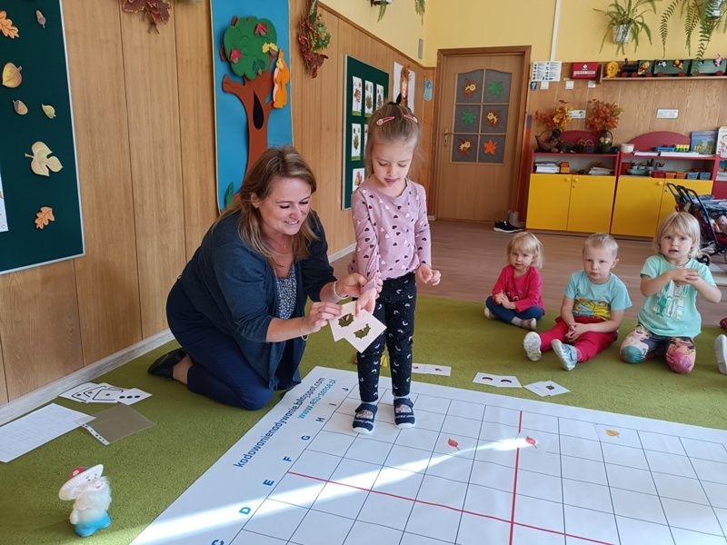 dzieci dobierają w pary rozłożone na macie kartoniki z obrazkami