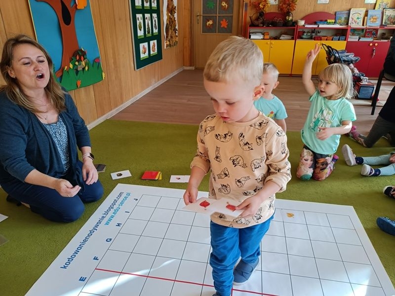 dzieci dobierają w pary rozłożone na macie kartoniki z obrazkami