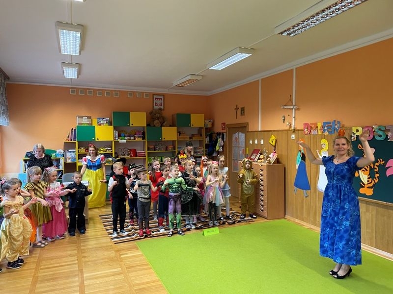 Dzieci w strojach bajkowcych obok stoi nauczyciel