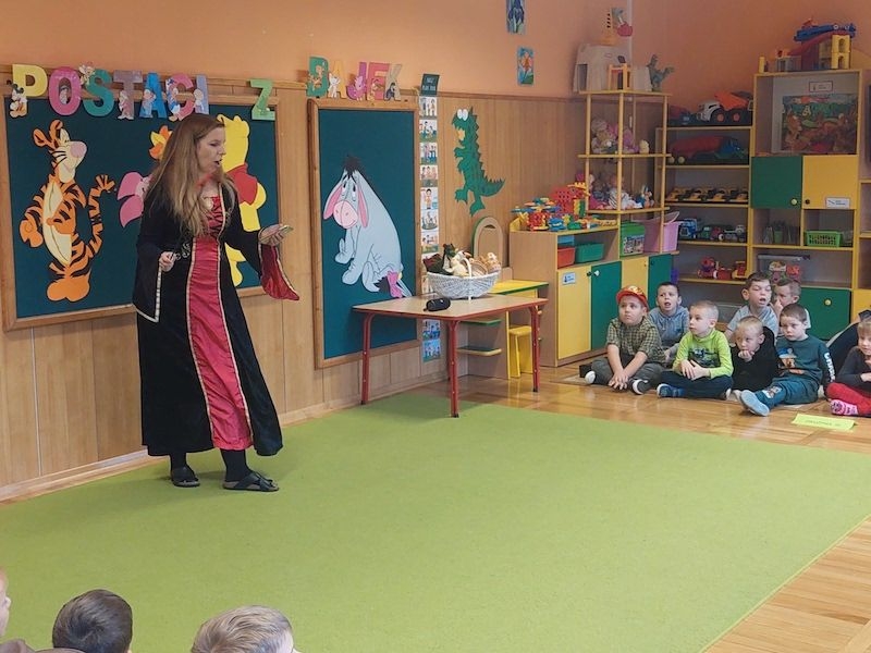 Dzieci w strojach bajkowcych obok stoi nauczyciel