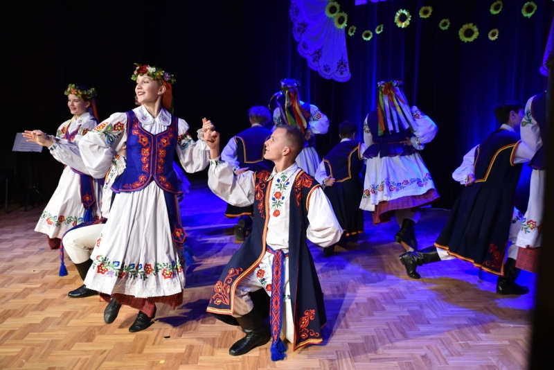 N a scenie zespół tańczy taniec ludowy.