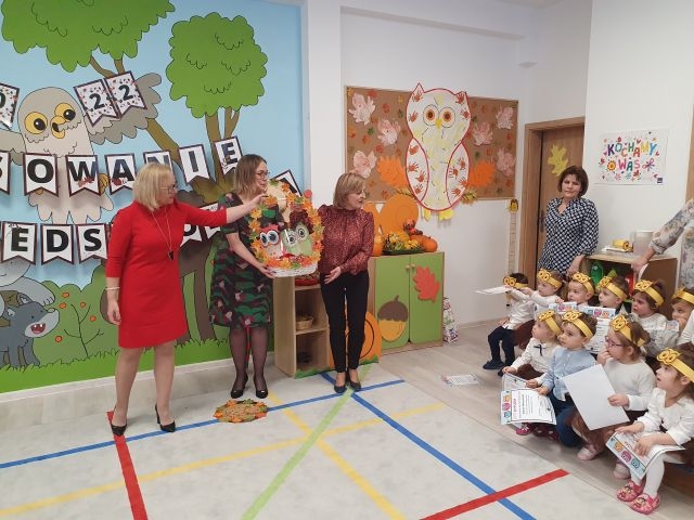 Pani dyrektor trzyma duży ołówek na ramieniu dziecka i dokonuje pasowania na przedszkolaka