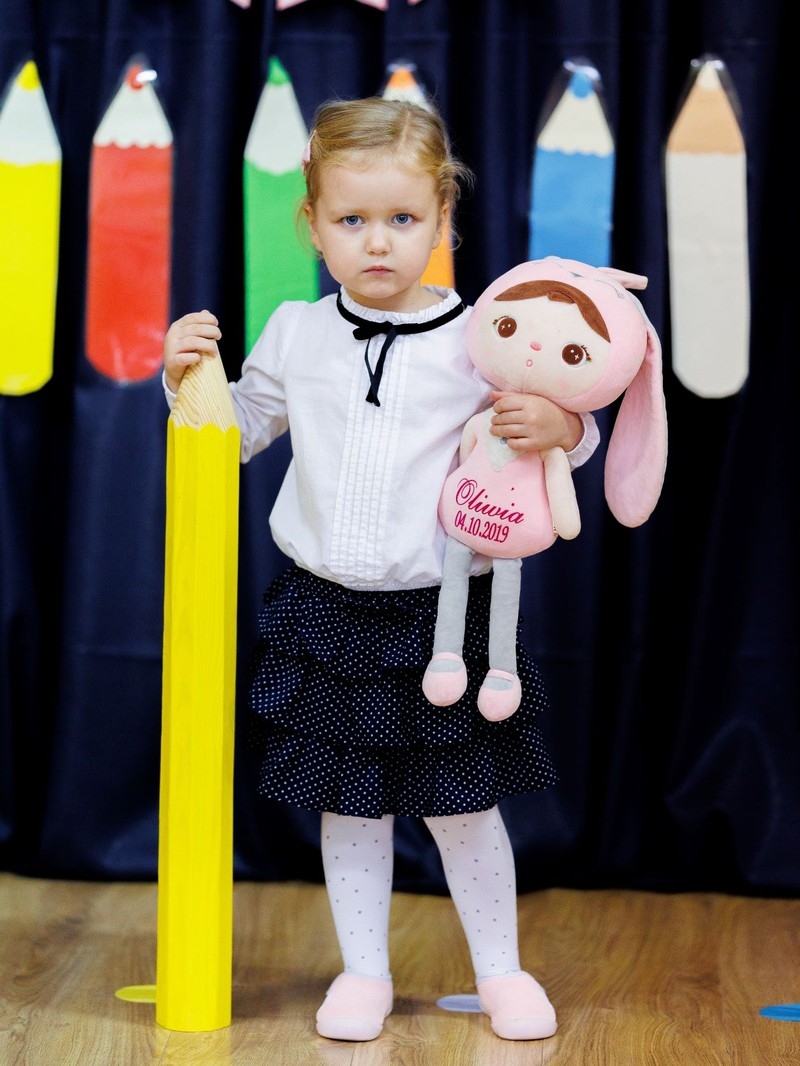 Dziewczynka trzyma w jednej dłoniuołówek, w drugiej pluszowego zająca