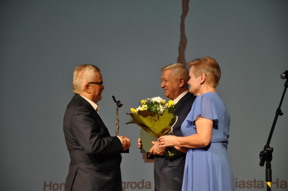 Kobieta i meżczyzna wręczają nagrodę lauratowi