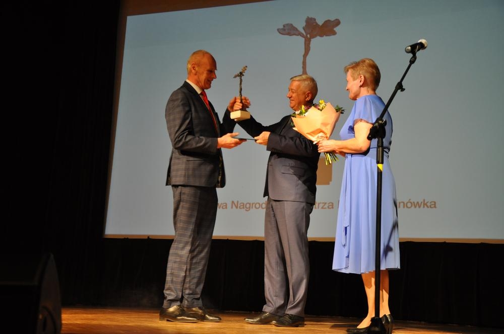 Kobieta i meżczyzna wręczają nagrodę lauratowi