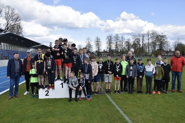 zdjęcie grupowe zawdoników, opiekunów i sędziów. Kilka osób stoi na podium.