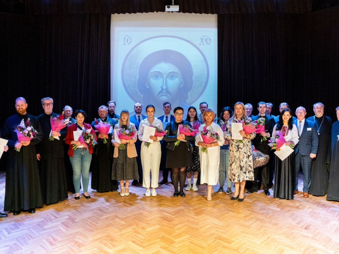 zdjęcie grupowe nagrodzonych festiwalu na scenie Hajnowskiego Domu Kultury, w tle wyświetlona ikona Chrystusa