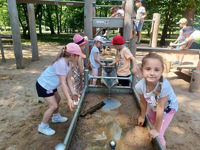 Przedszkolaki spacerują alejkami ogrodu zoologicznego.