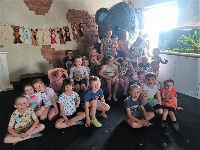 Dzieci pozują grupami przy wielkim misiu.