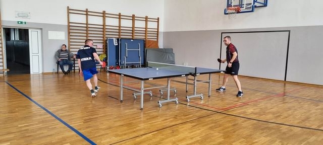 mężczyźni grający w tenisa stołowego na sali gimnastycznej