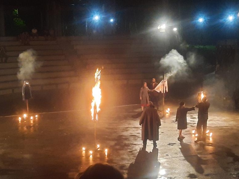 aktorzy na płycie amfiteatru, scena oswietlona ogniem