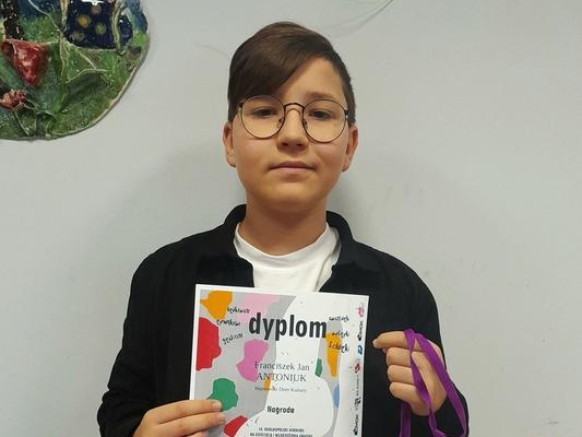 młody chłopak trzyma dyplom