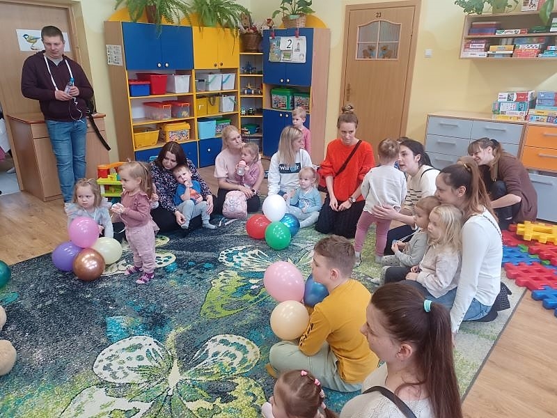 dzieci z opiekunami siedza na dywanie