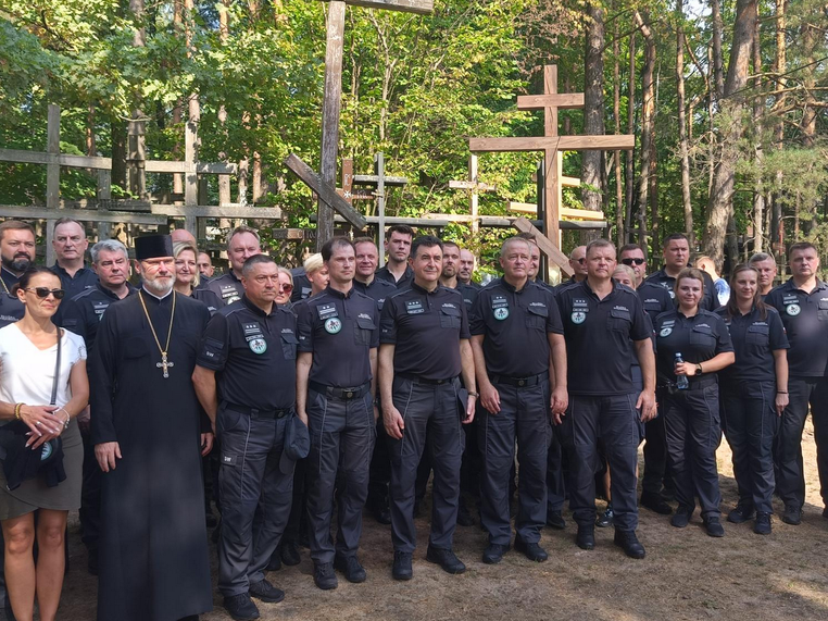 grupa ludzi w mundurach. W tle widać krzyże