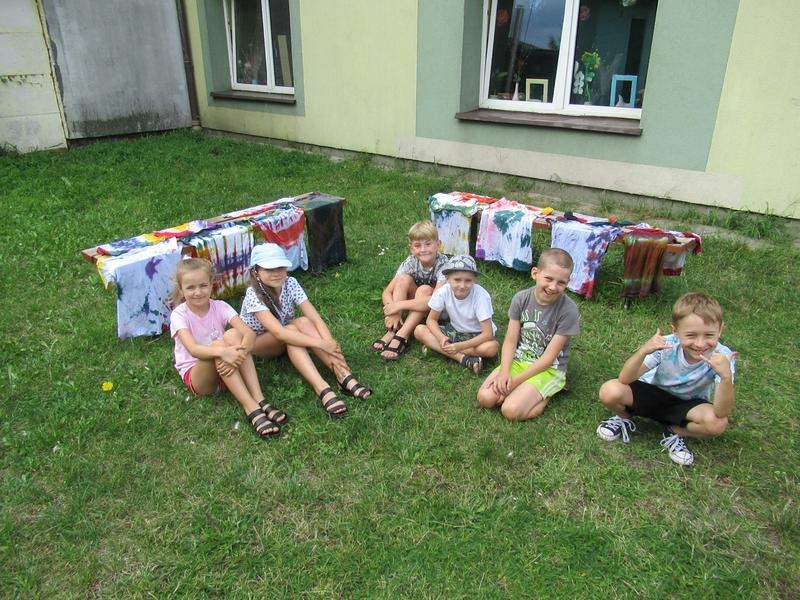 Dzieci pozują na tle własnoręcznie farbowanych koszulek metodą TIE-DYE.