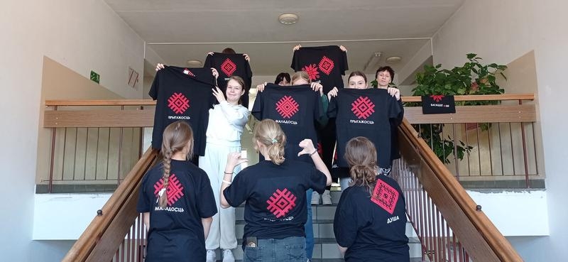 młodzież stoi na schodach i prezentuje koszulki z nadrukami