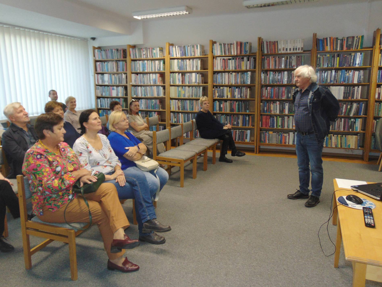 mężczyzna stoi przed publicznością w czytelni miejskiej