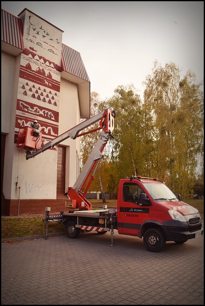 mężczyzna na podnośniku wykonuje mural