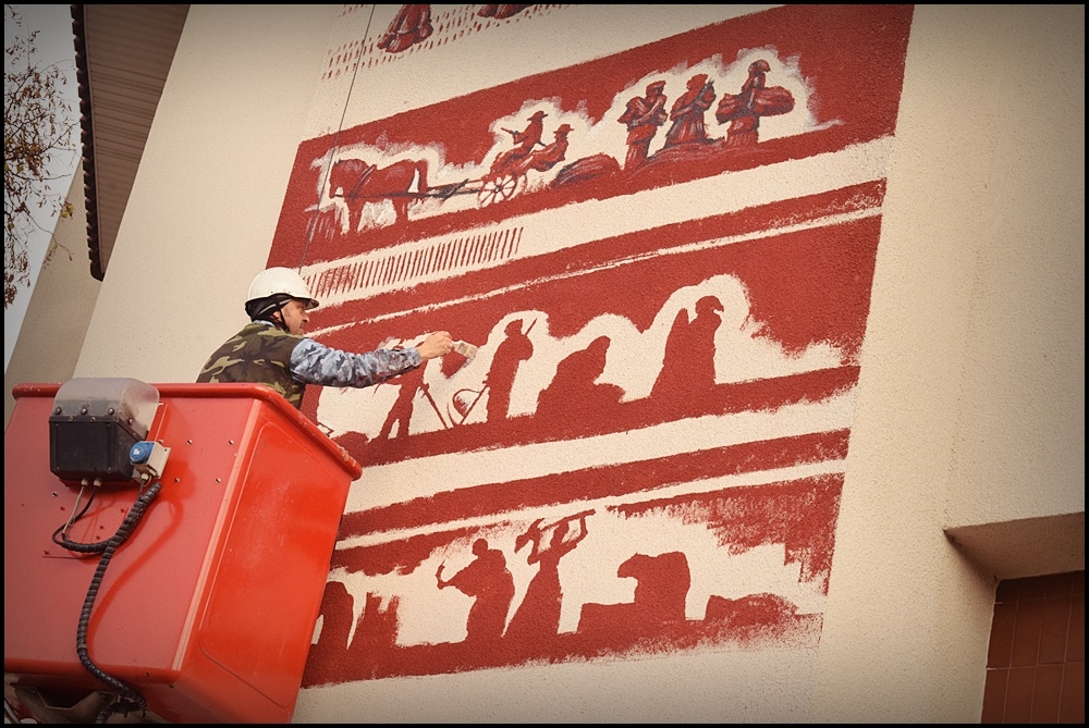 mężczyzna na podnośniku wykonuje mural