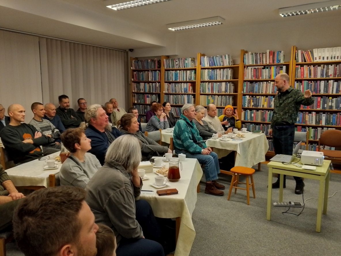 prowadzący i słuchacze na spotkaniu w bibliotece