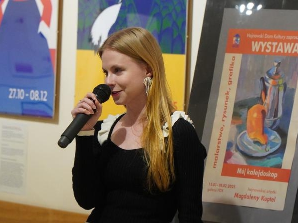 kobieta z mikrofonem stoi przy swoich pracach