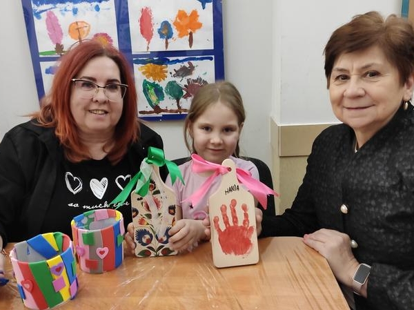 dwie kobiety i dziewczynka prezentują wykonane prace