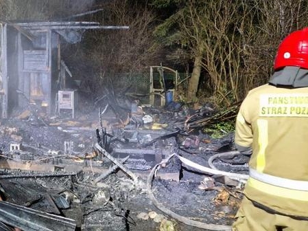 strażak przy zwęglonym domku letniskowym