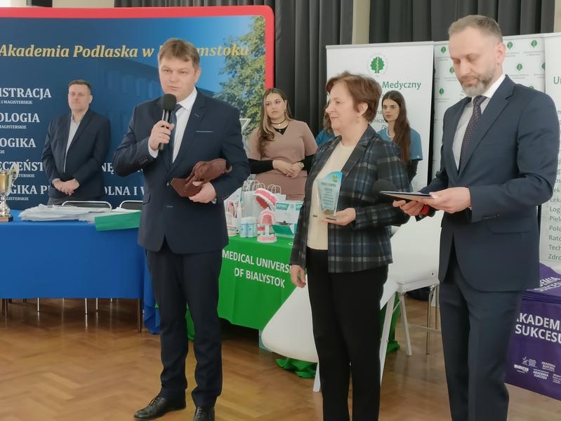 otwarcie targów. Burmistrz przy mikrofonie. W tle widać stoiska wystawiennicze uczelni