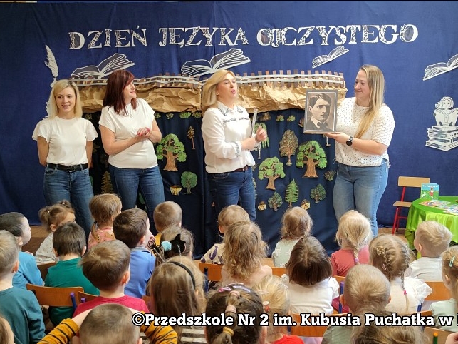 Cztery panie pokazują dzieciom wizerunek mężczyzny. W tel widać tematyczną scenografię