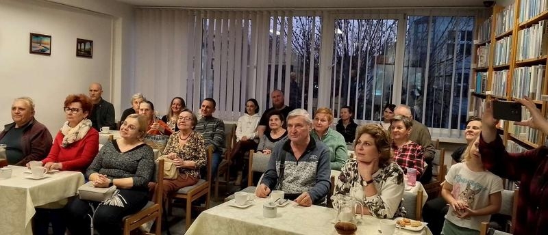 słuchacze na spotkaniu w sali bibliotecznej