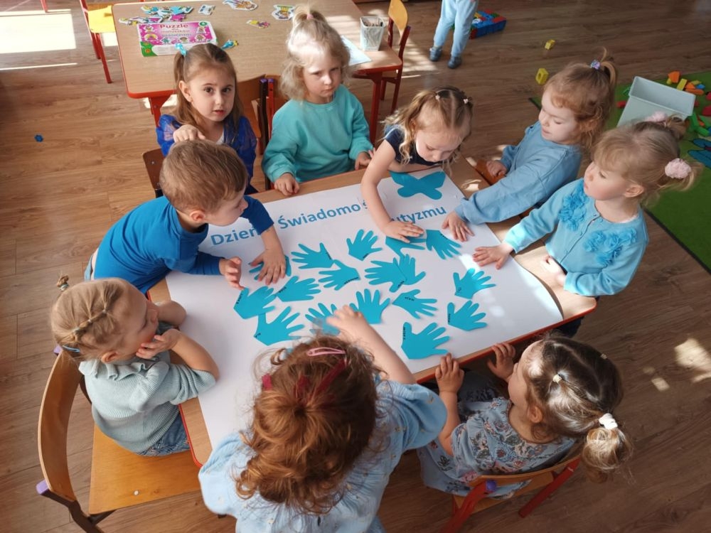 dzieci siedzą na dywanie i pracują z kartami pracy