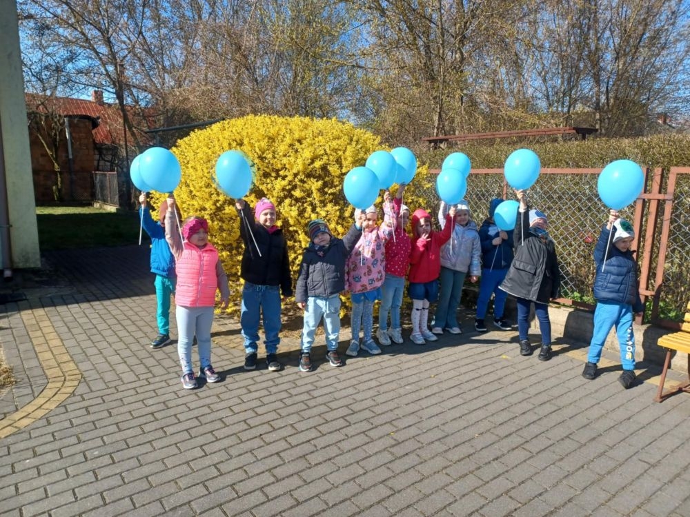 dzieci z niebieskimi balonikami przed przedszkolem