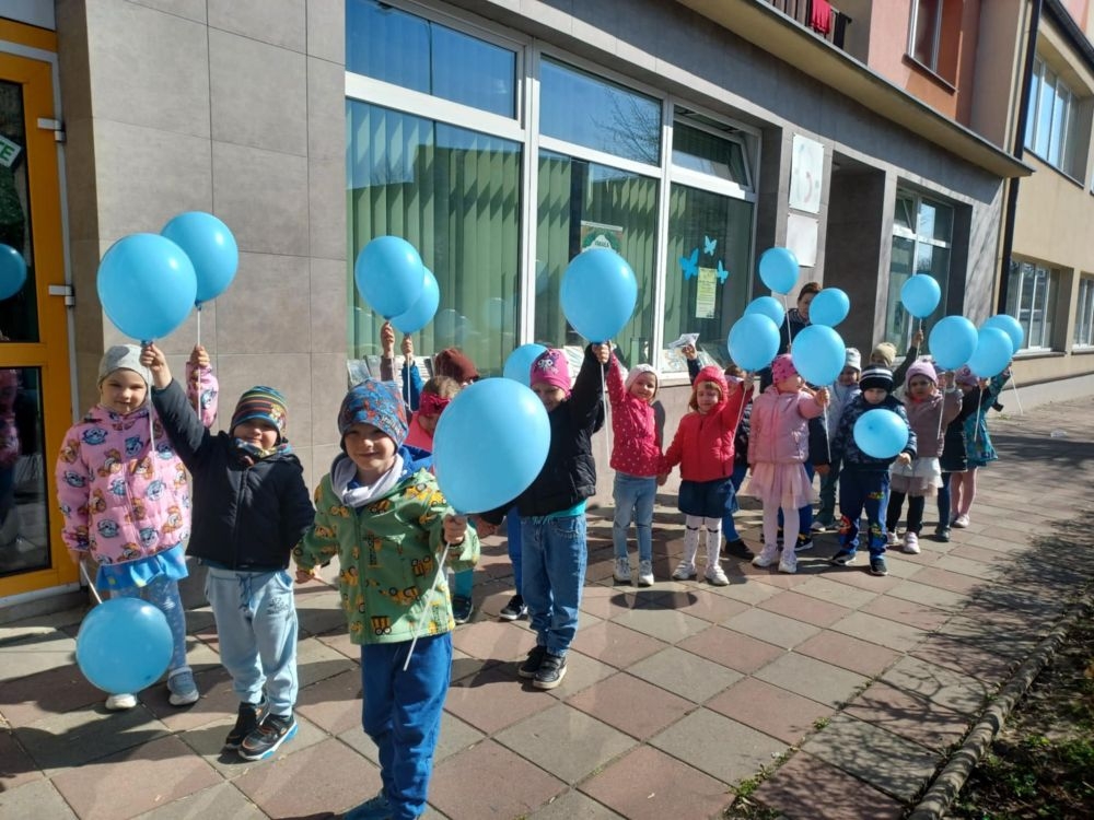 maszerujace dzieci z niebieskimi balonikami