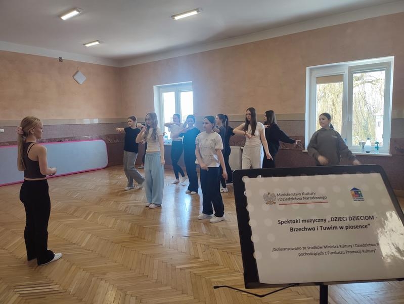 grupa tancerzy na próbie. Na pierwszym planie tablica projektowa