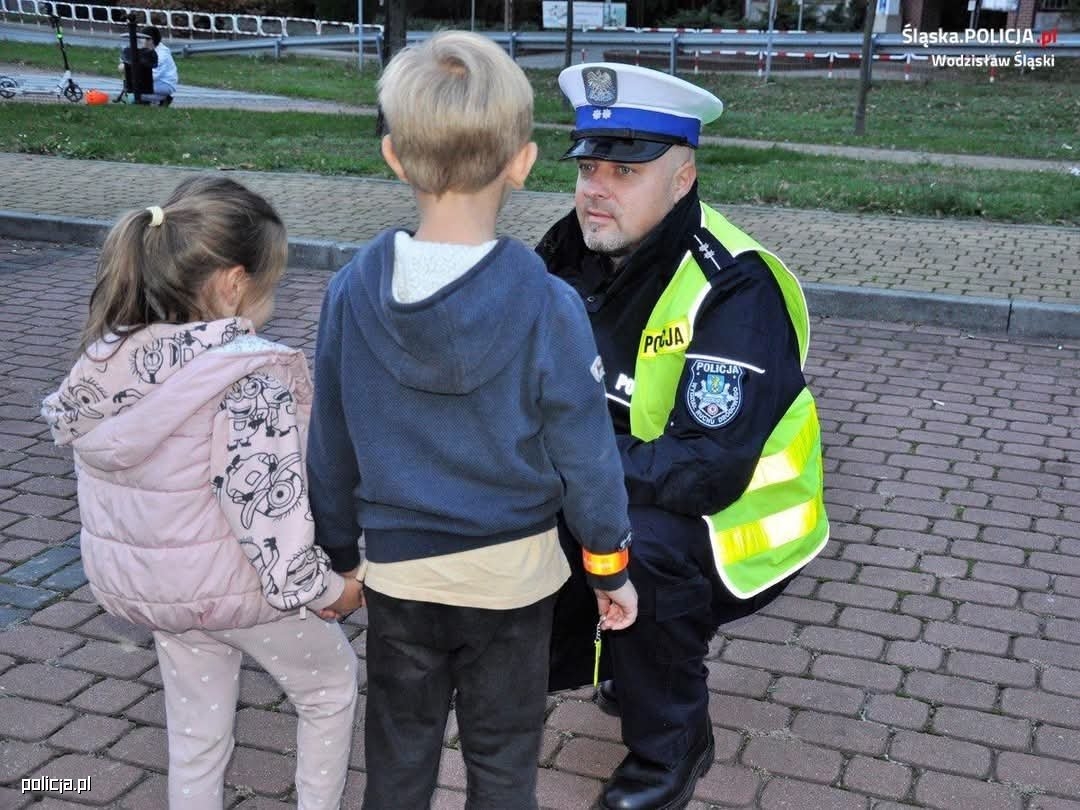 policjant w mundurze kuca przy dwójce dzieci