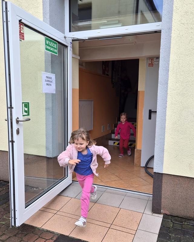 dzieci wybiegają przez drzwi ewakuacyjne
