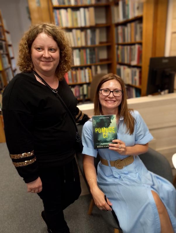 dwie kobiety. jedna trzyma książkę