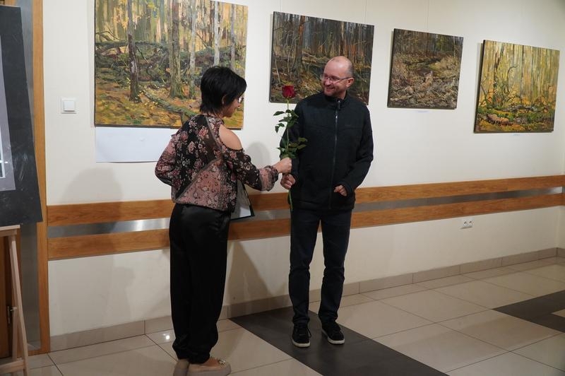 wręczenie podziękowań. W tle wystawa.