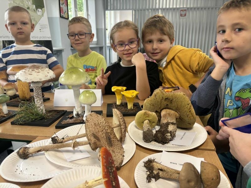 Dzieci pozują do zdjęcia przy wystawie grzybów