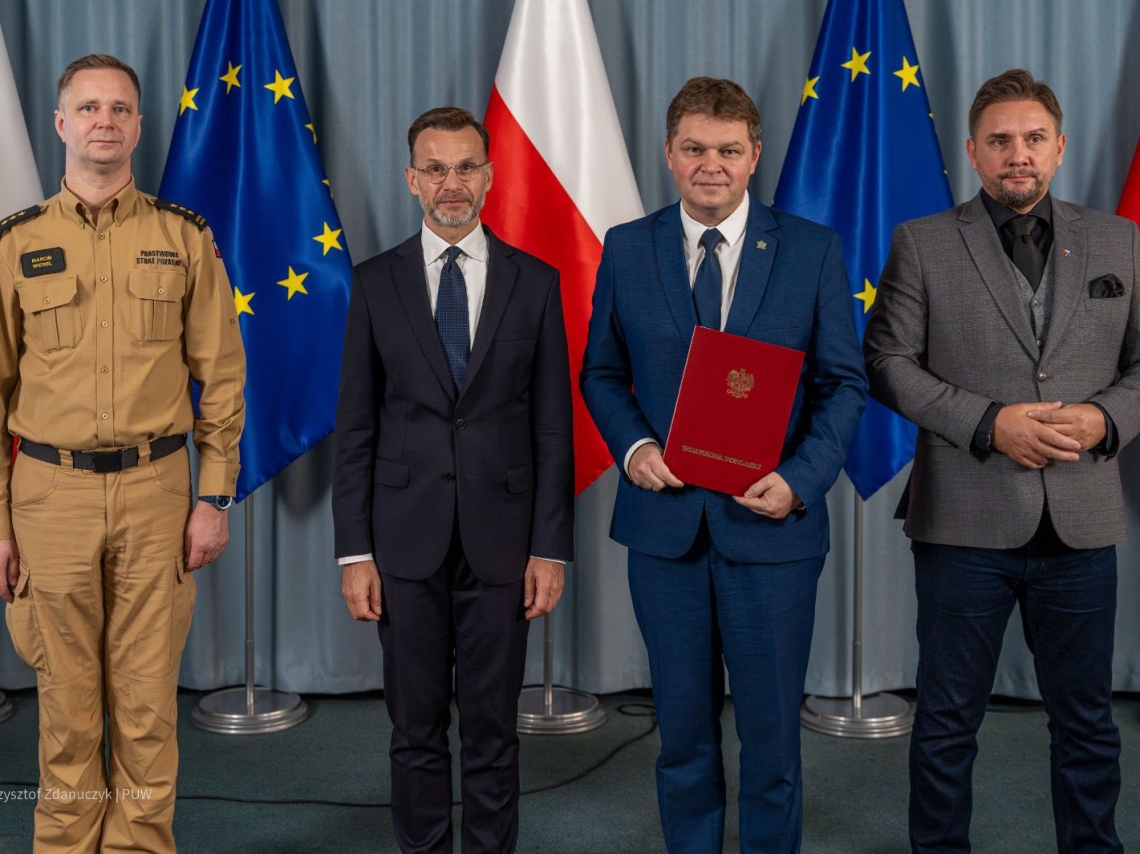 burmistrz miasta z wojewodą i wicewojewodą, przedstawicielem straży pożarnej na tle flag