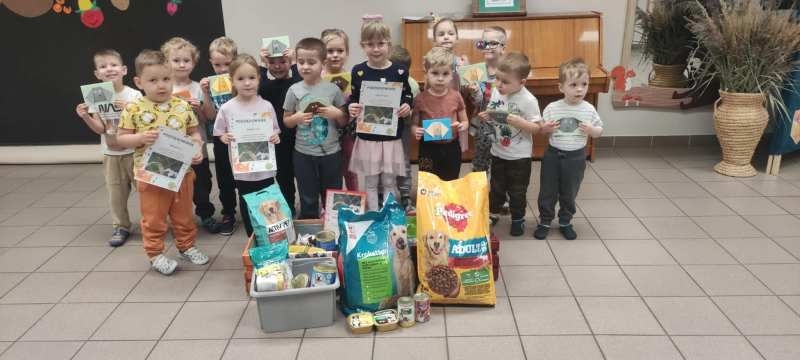 dzieci stoją przy zebranej karmie dla zwierząt