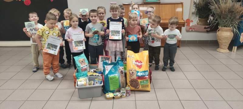 dzieci stoją przy zebranej karmie dla zwierząt