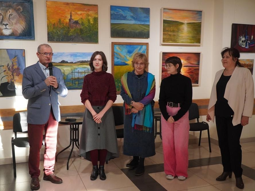 artyści podczas otwarcia wernisażu. W tle widać wystawę ich prac