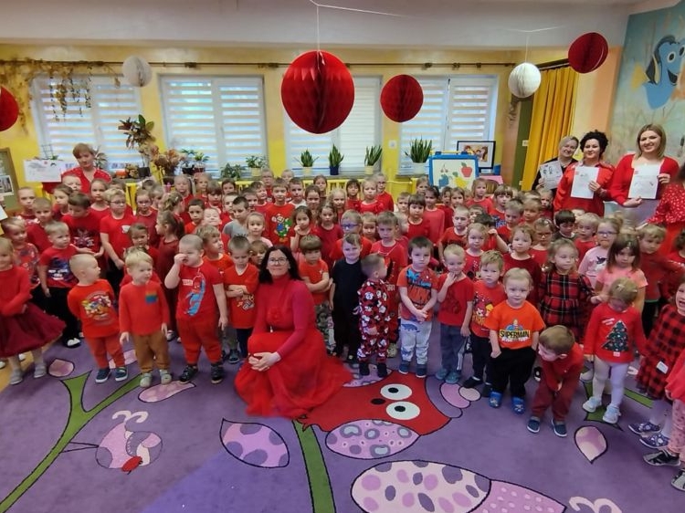 Wszyscy uczestnicy kampanii pozują do zdjęcia. Dzieci oraz kadra pedagogiczna jest ubrana na czerwono. Czerwony jest kolorem kampanii.