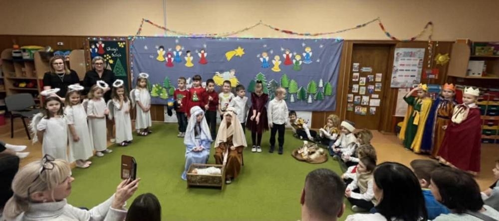 jasełka bożonarodzeniowe w wykonaniu grupy piątej na tle bożonarodzeniowej dekoracji