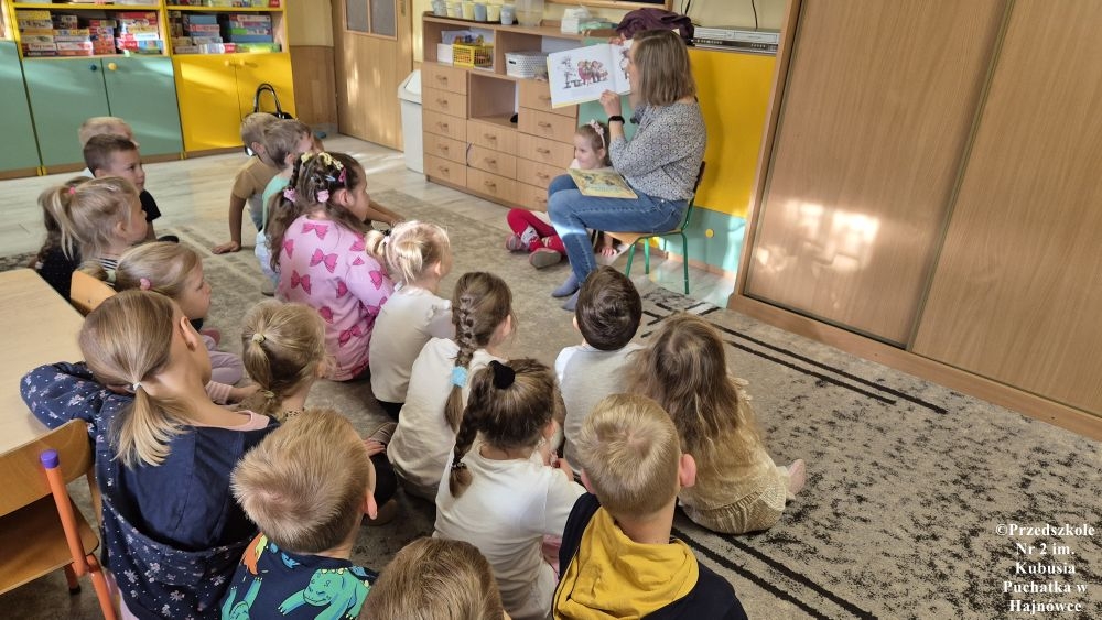 kobieta pokazuje dzieciom książkę
