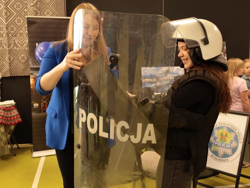 Przy stoisku policji - uczennica przymierza policyjne umundurowanie