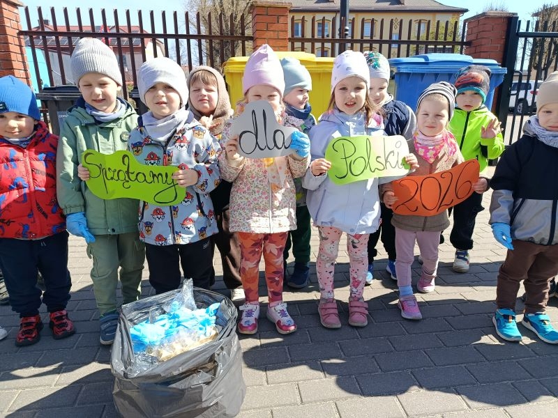 dzieci trzymają kartki z napisem "Sprzątamy dla Polski"
