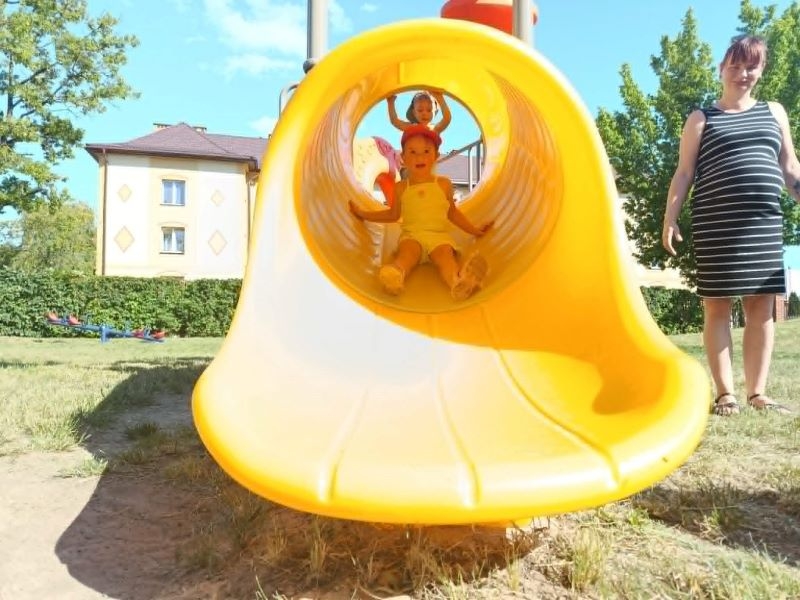 dzieci znajdują się w ogrodzie przedszkolnym, gdzie korzystają z urządzeń terenowych.