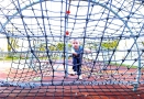 chłopczyk wspinający się po konstrukcji linowej, mieszczącej się na Rodzinnej Strefie Zabaw